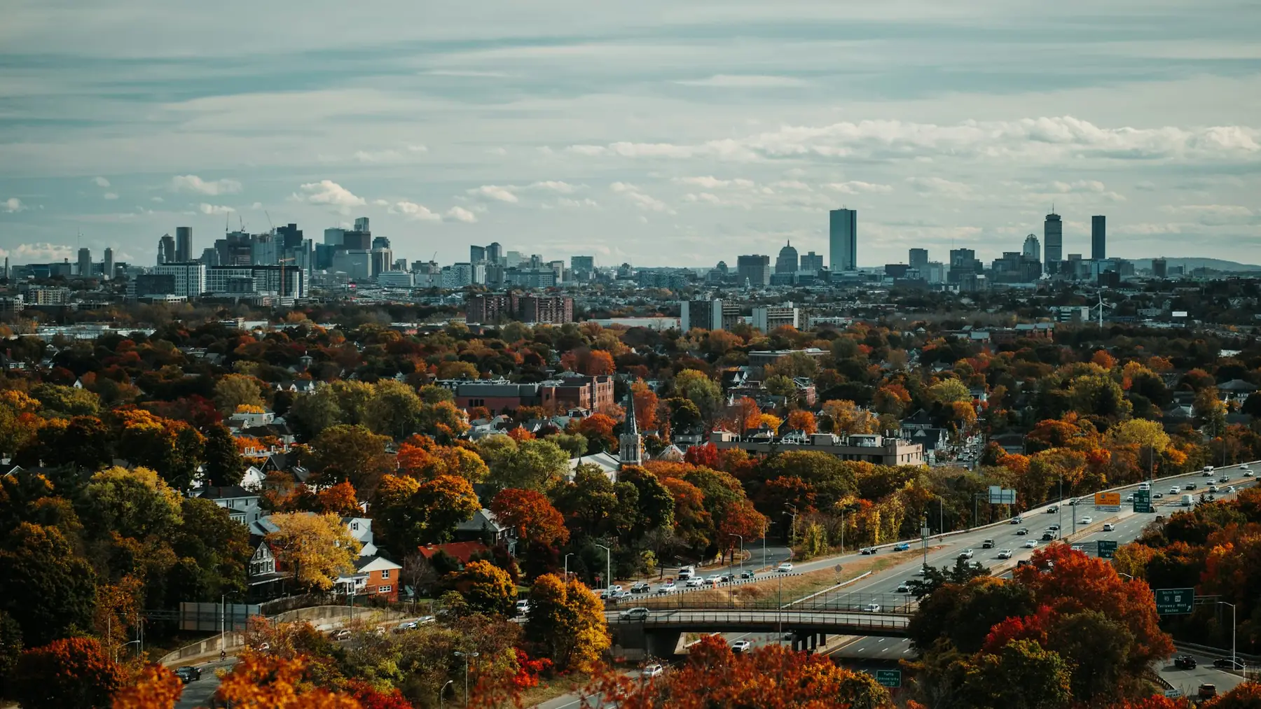 A tree-lined Greater Boston neighborhood in autumn, skyline in the distance